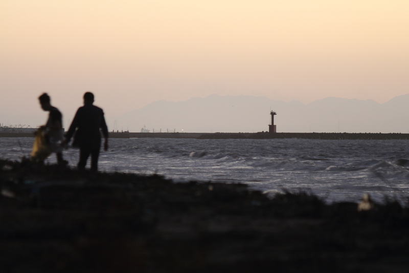 台風が過ぎ去った後の伊勢湾の海岸の風景を撮影した写真②沢山のゴミが打ち上げらている海岸を散歩する人たち。